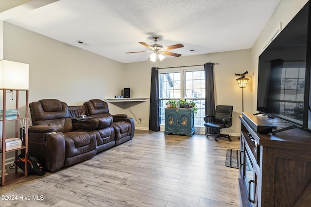 living room featuring ceiling fan, a textured ceiling, and light hardwood / wood-style flooring