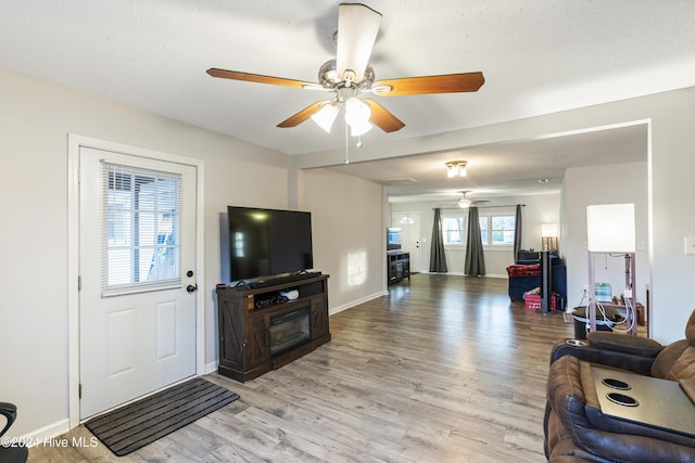 living room featuring ceiling fan, a healthy amount of sunlight, light wood-type flooring, and a textured ceiling