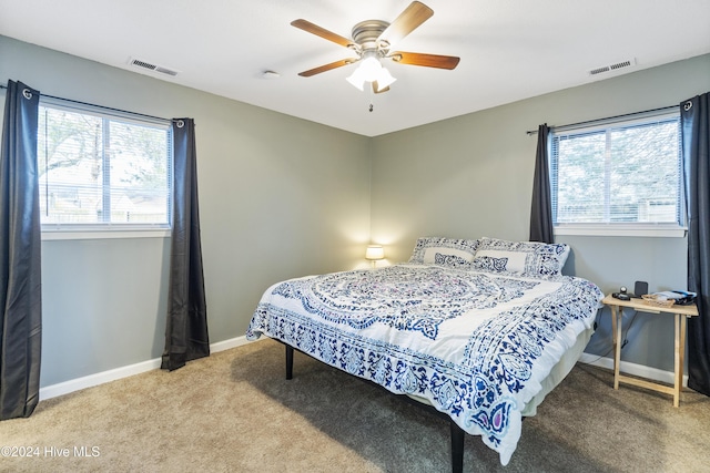 bedroom featuring multiple windows, light colored carpet, and ceiling fan