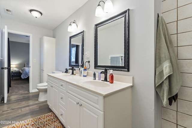 bathroom with a textured ceiling, vanity, hardwood / wood-style flooring, and toilet