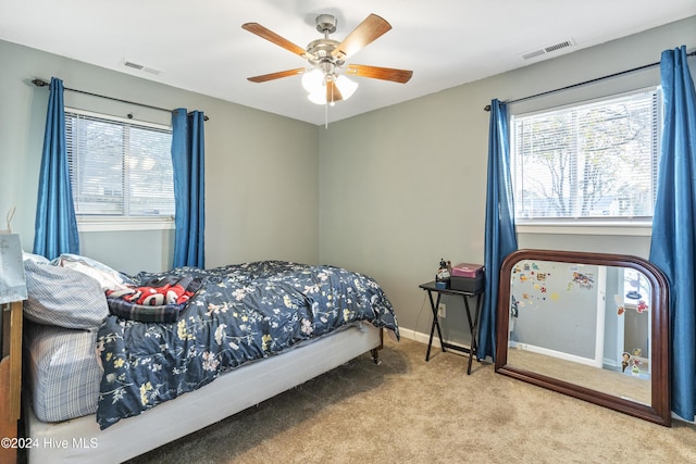 carpeted bedroom with multiple windows and ceiling fan