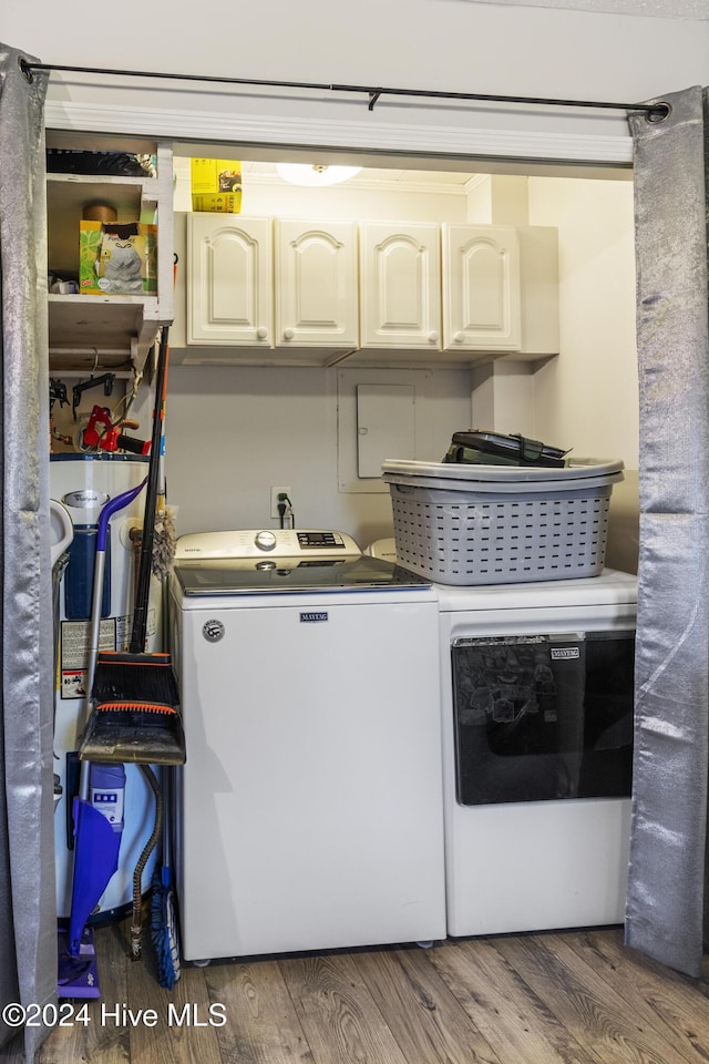 clothes washing area with hardwood / wood-style flooring, washer and clothes dryer, and cabinets