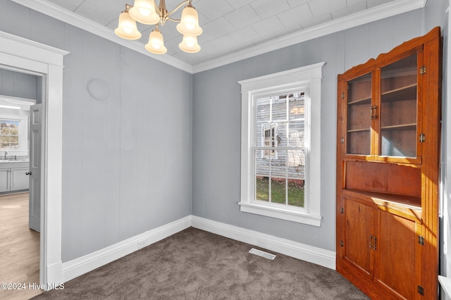 unfurnished dining area with a notable chandelier, a healthy amount of sunlight, carpet floors, and crown molding