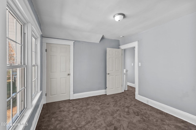 unfurnished bedroom with dark colored carpet