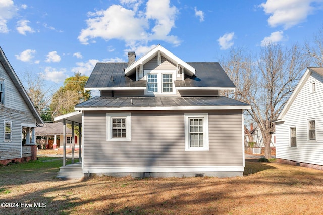 rear view of property featuring a lawn and covered porch