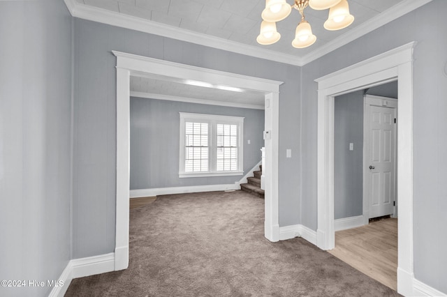 empty room featuring carpet floors, crown molding, and a chandelier