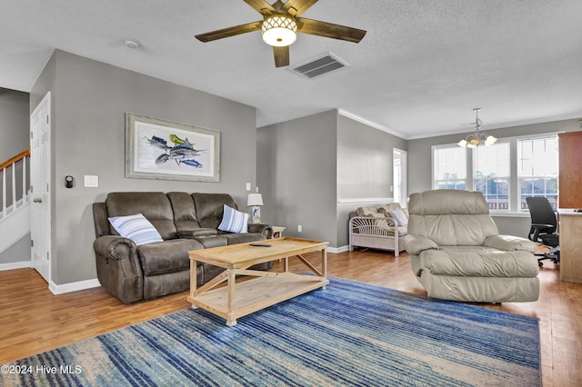 living room featuring ceiling fan with notable chandelier, light hardwood / wood-style floors, ornamental molding, and a textured ceiling