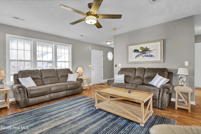 living room featuring wood-type flooring, a textured ceiling, and ceiling fan