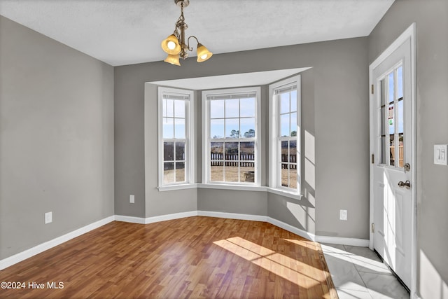 foyer entrance featuring light hardwood / wood-style flooring, a textured ceiling, and an inviting chandelier