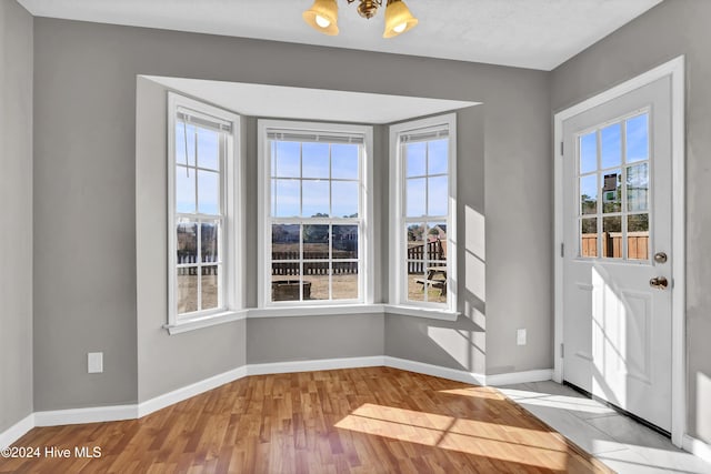 foyer entrance featuring a textured ceiling, light hardwood / wood-style floors, and an inviting chandelier