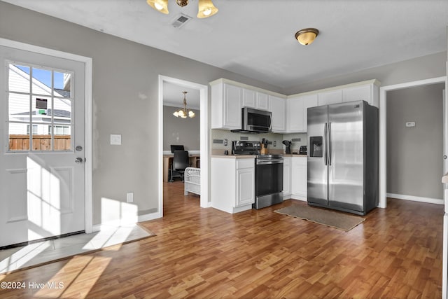 kitchen featuring backsplash, stainless steel appliances, light hardwood / wood-style flooring, a notable chandelier, and white cabinets