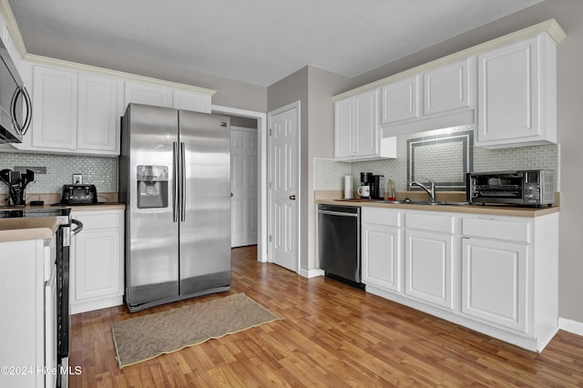 kitchen with light hardwood / wood-style flooring, white cabinets, stainless steel appliances, and sink