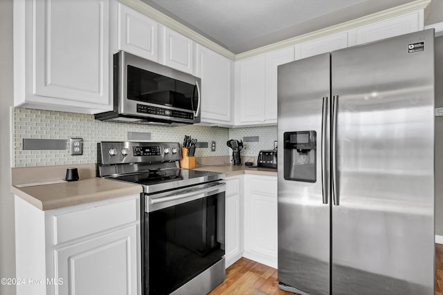 kitchen with decorative backsplash, light hardwood / wood-style floors, white cabinetry, and stainless steel appliances