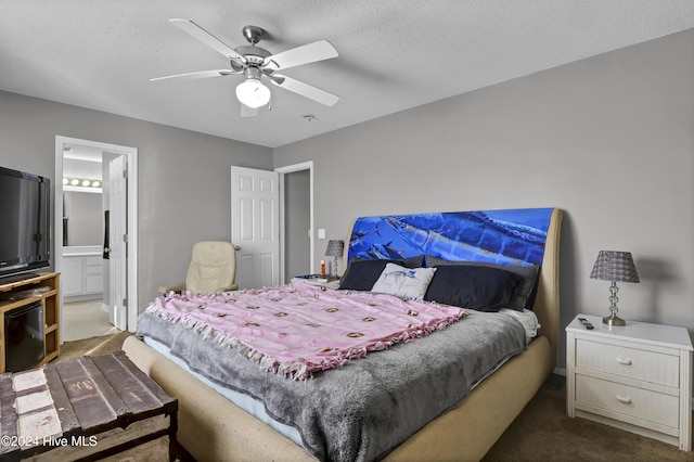 bedroom featuring a textured ceiling, ceiling fan, dark carpet, and ensuite bathroom