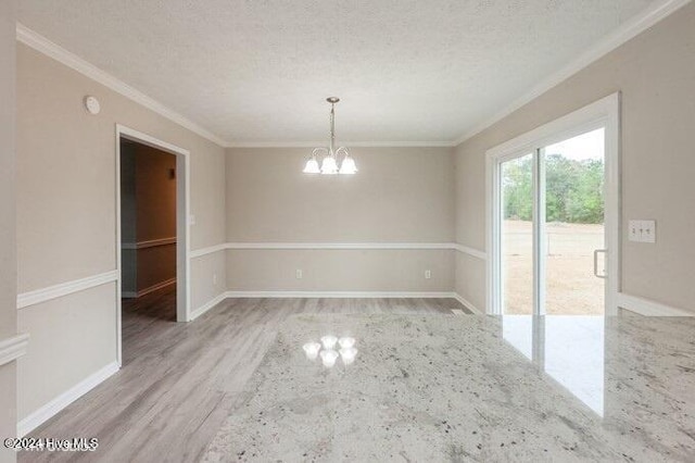 spare room featuring hardwood / wood-style flooring, ornamental molding, a textured ceiling, and a chandelier