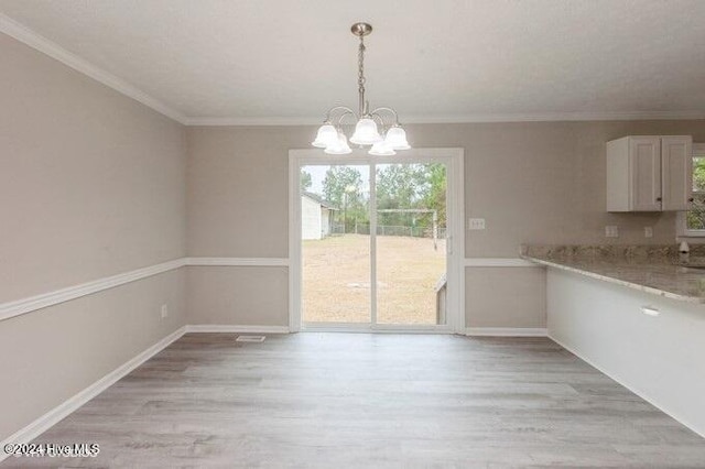 unfurnished dining area featuring ornamental molding, a notable chandelier, and light wood-type flooring