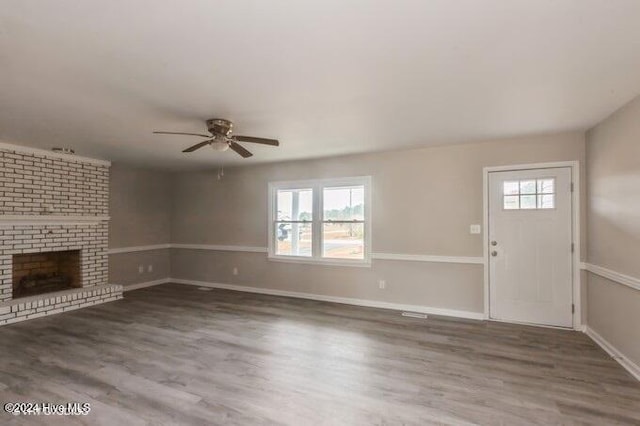 unfurnished living room with ceiling fan, plenty of natural light, dark hardwood / wood-style floors, and a brick fireplace