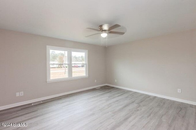 empty room with ceiling fan and light hardwood / wood-style flooring