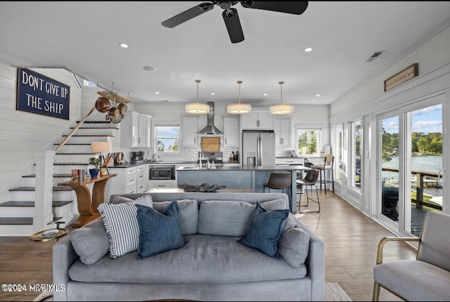 living room featuring ceiling fan, light hardwood / wood-style floors, ornamental molding, and sink