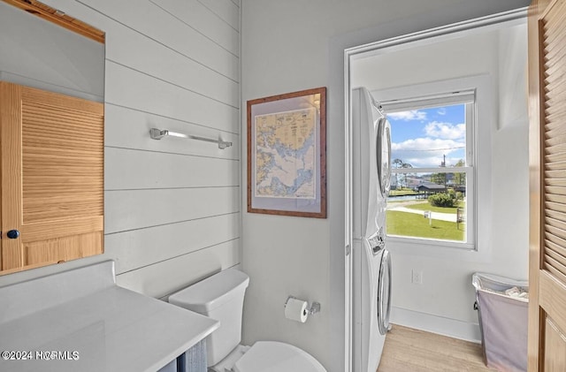 bathroom featuring stacked washing maching and dryer and wood-type flooring