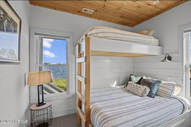 carpeted bedroom featuring a water view, ornamental molding, and wood ceiling