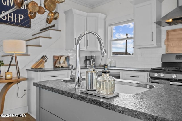 kitchen with gas range, white cabinetry, and wall chimney exhaust hood