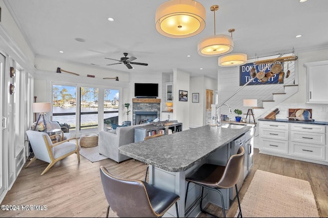 kitchen with ceiling fan, crown molding, sink, white cabinets, and light hardwood / wood-style floors