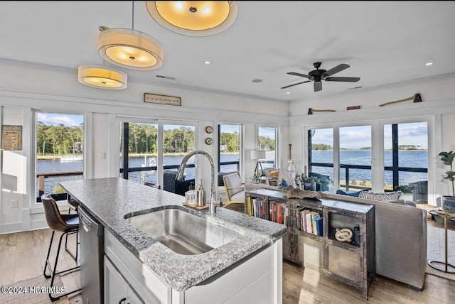 kitchen with white cabinets, a water view, light hardwood / wood-style floors, and sink