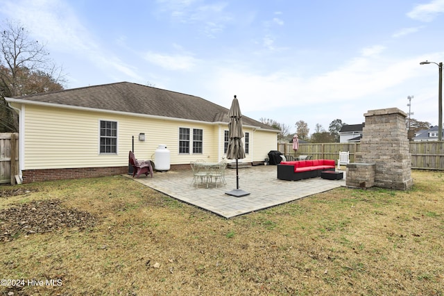 back of house with an outdoor living space with a fireplace, a patio area, and a lawn