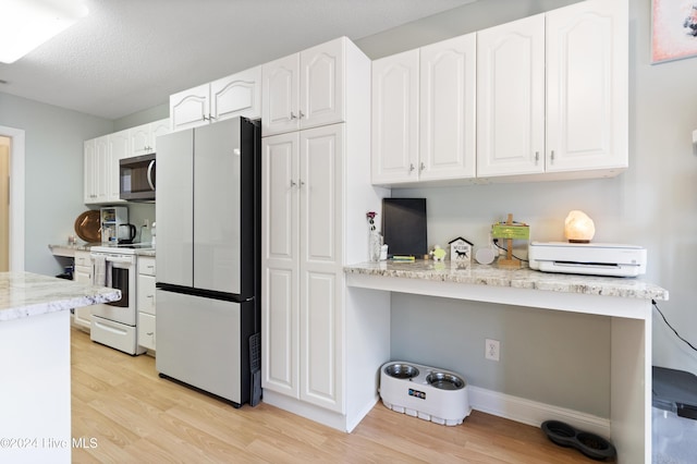 kitchen featuring white cabinetry, light stone countertops, light hardwood / wood-style flooring, a textured ceiling, and white appliances