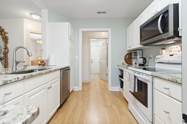 kitchen with light stone countertops, sink, stainless steel appliances, light hardwood / wood-style floors, and white cabinets