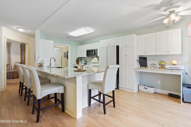 kitchen featuring white cabinetry, a kitchen bar, kitchen peninsula, and sink