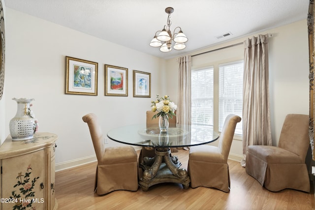 dining space featuring an inviting chandelier, a textured ceiling, and light hardwood / wood-style flooring