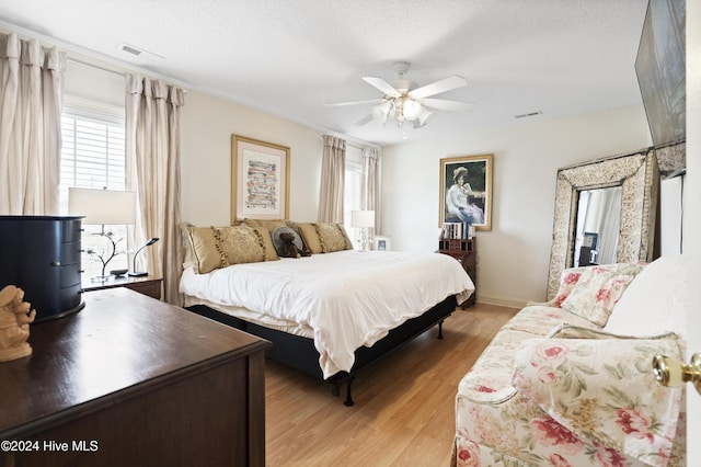 bedroom featuring ceiling fan, a textured ceiling, and light wood-type flooring