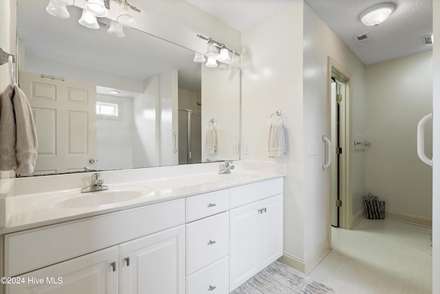 bathroom with vanity, a textured ceiling, tile patterned floors, and walk in shower