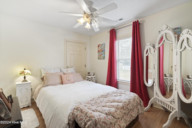 bedroom with hardwood / wood-style flooring, ceiling fan, and a textured ceiling