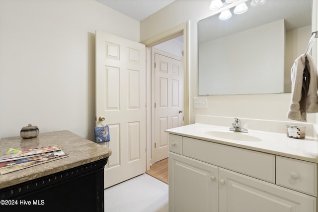 bathroom with wood-type flooring, vanity, and a textured ceiling