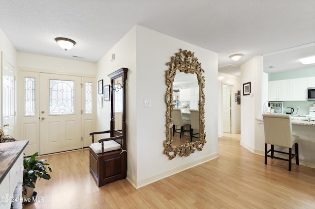 entrance foyer featuring a textured ceiling and light hardwood / wood-style flooring