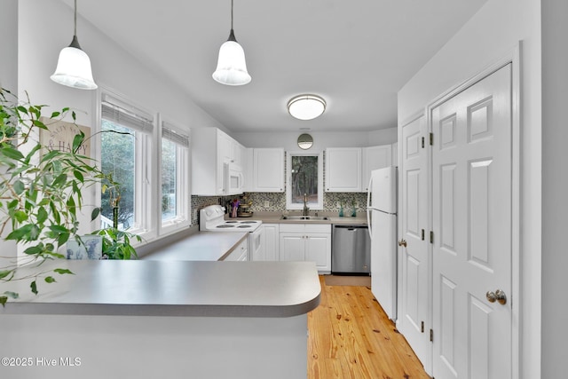 kitchen with kitchen peninsula, sink, pendant lighting, and white appliances