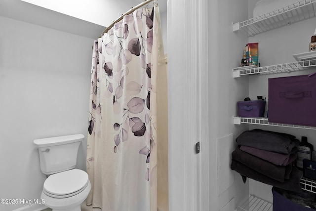 bathroom with a shower with shower curtain and toilet