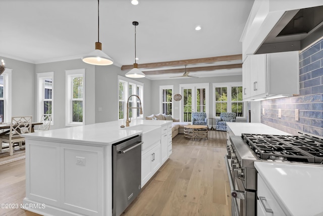 kitchen featuring ceiling fan, stainless steel appliances, light hardwood / wood-style flooring, an island with sink, and decorative light fixtures