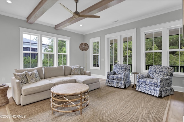 living room with ceiling fan, beamed ceiling, a healthy amount of sunlight, and hardwood / wood-style flooring