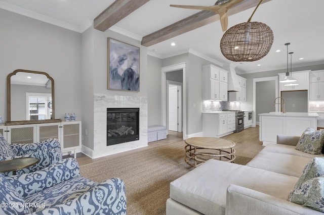 living room with light hardwood / wood-style floors, sink, a premium fireplace, and beam ceiling