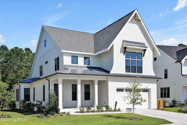 modern farmhouse with a front yard, a porch, and a garage