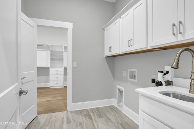 laundry area with sink, cabinets, washer hookup, electric dryer hookup, and light hardwood / wood-style flooring