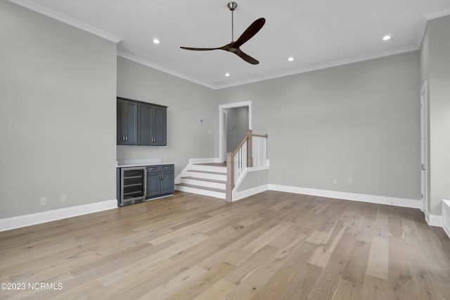 unfurnished living room with wine cooler, crown molding, ceiling fan, and light wood-type flooring