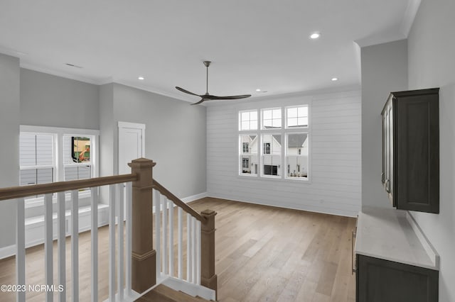 hallway featuring light hardwood / wood-style floors, crown molding, and wooden walls