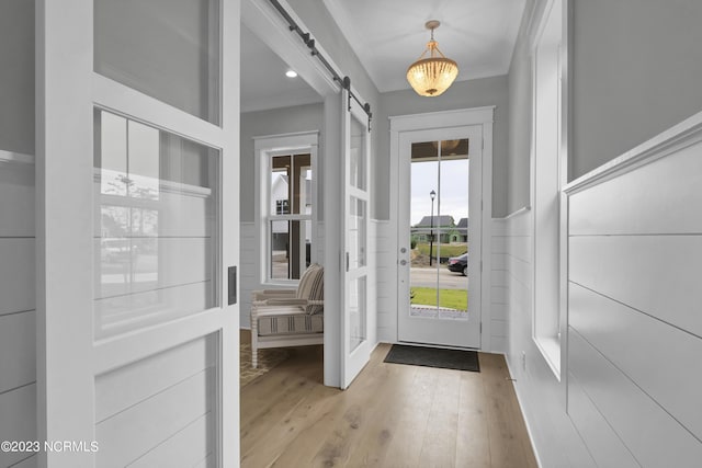 entryway with a barn door and light hardwood / wood-style floors