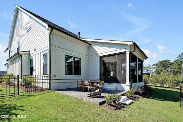 back of property with a lawn, a sunroom, and a patio