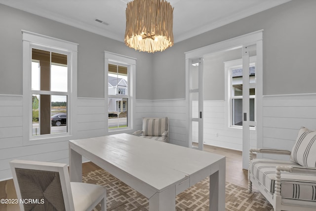 dining space featuring wood-type flooring, crown molding, and a notable chandelier